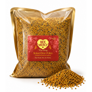 A clear stand-up pouch filled with golden yellow bee pollen granules, with a red and gold Bee Mercy label on the front. A small pile of the same pollen granules sits in front of the bag on a clean white background.