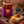 A jar of Bee Mercy Heather raw honey displayed on a rustic stone surface with a slice of blue cheese, honey dipper, grapes, and a small bowl of blackberries, surrounded by heather flowers in an outdoor field.