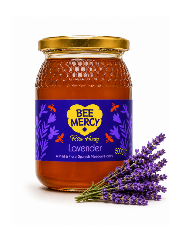 A 500g glass jar of Bee Mercy Lavender Raw Honey with a gold lid and a purple label, styled with a bouquet of fresh lavender sprigs on a white background.