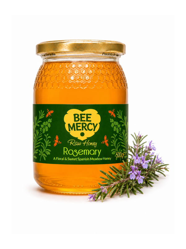 A 500g glass jar of Bee Mercy Raw Honey Rosemary, featuring a green and yellow label, a gold lid, and a sprig of fresh rosemary on a white background.