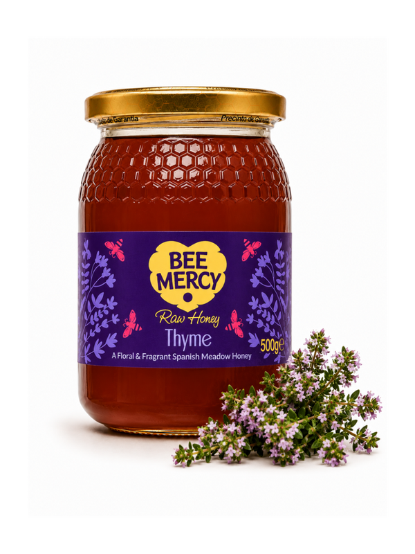 A 500g glass jar of Bee Mercy Raw Honey Thyme on a white background, styled with a small sprig of fresh thyme in front of the label.