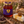 A jar of Bee Mercy Thyme Honey is displayed on a rustic wooden table alongside a slice of Brie cheese with honey drizzle, a honey dipper, olives, and lavender flowers, set against a blurred field at sunset.