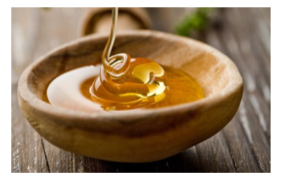 Raw honey dripping in wooden bowl
